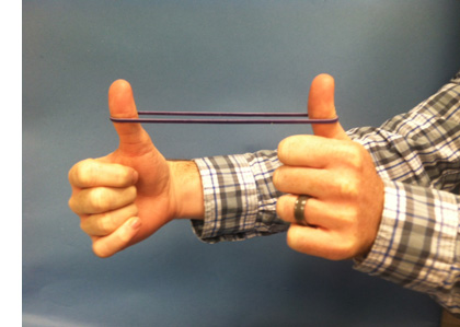a student stretches a rubber band between his two thumbs
